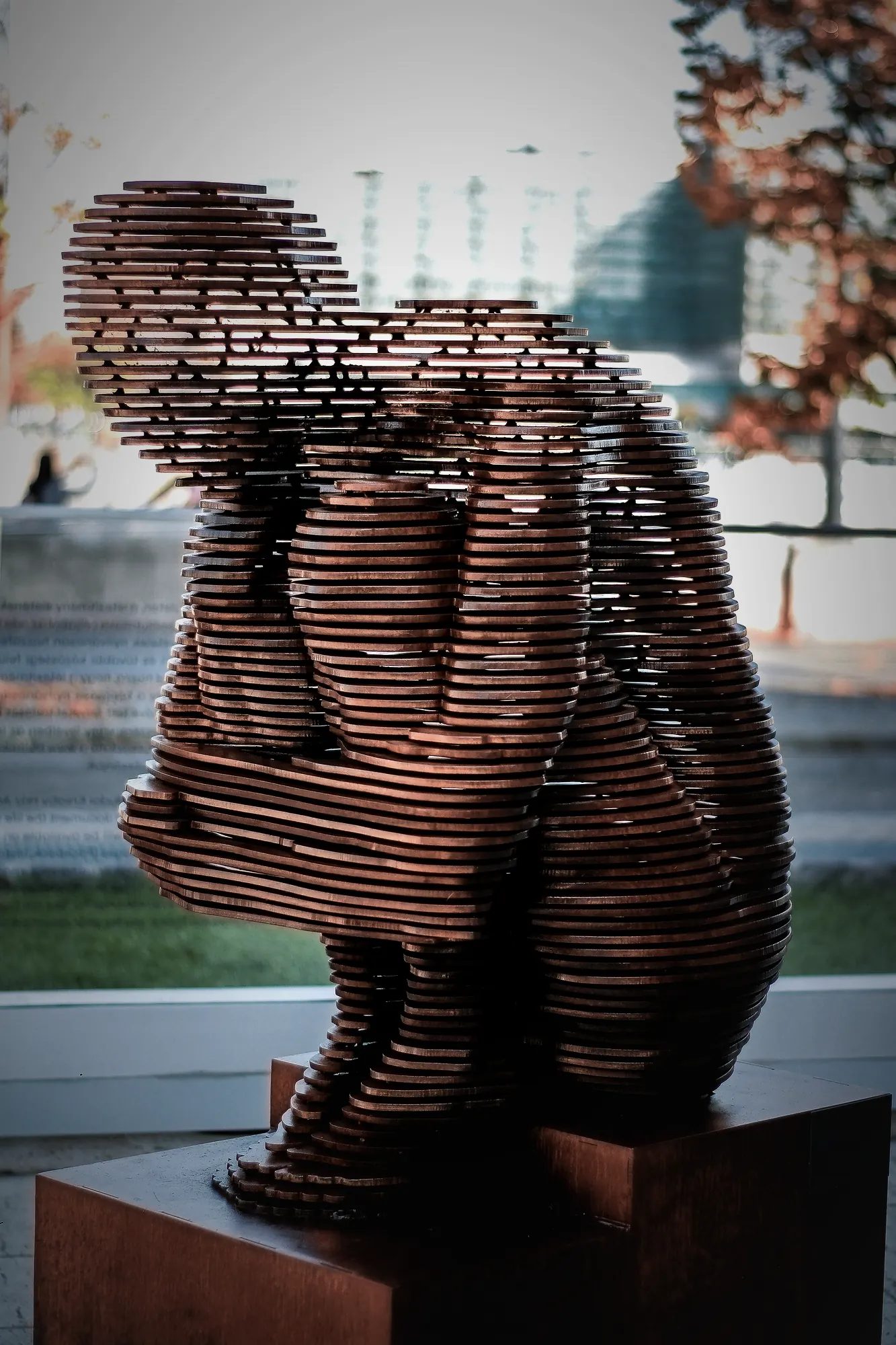 A sculpture of a seated figure built from stacked copper slices